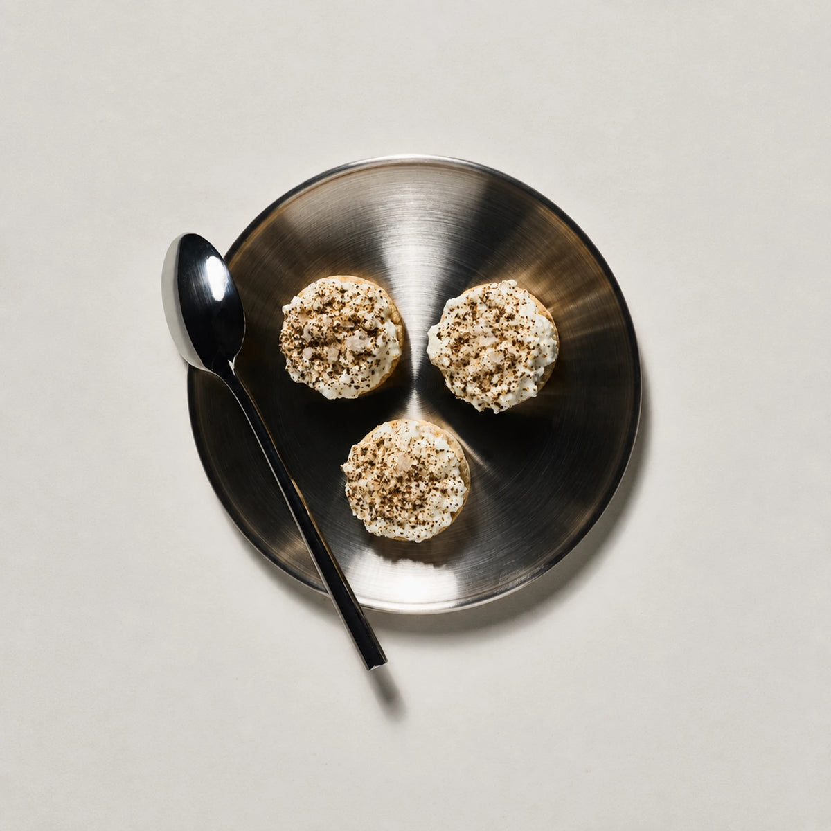 Three Subtle Snacks Hint of Salt Protein Rice Cake Minis with a creamy topping and cracked pepper on a plate