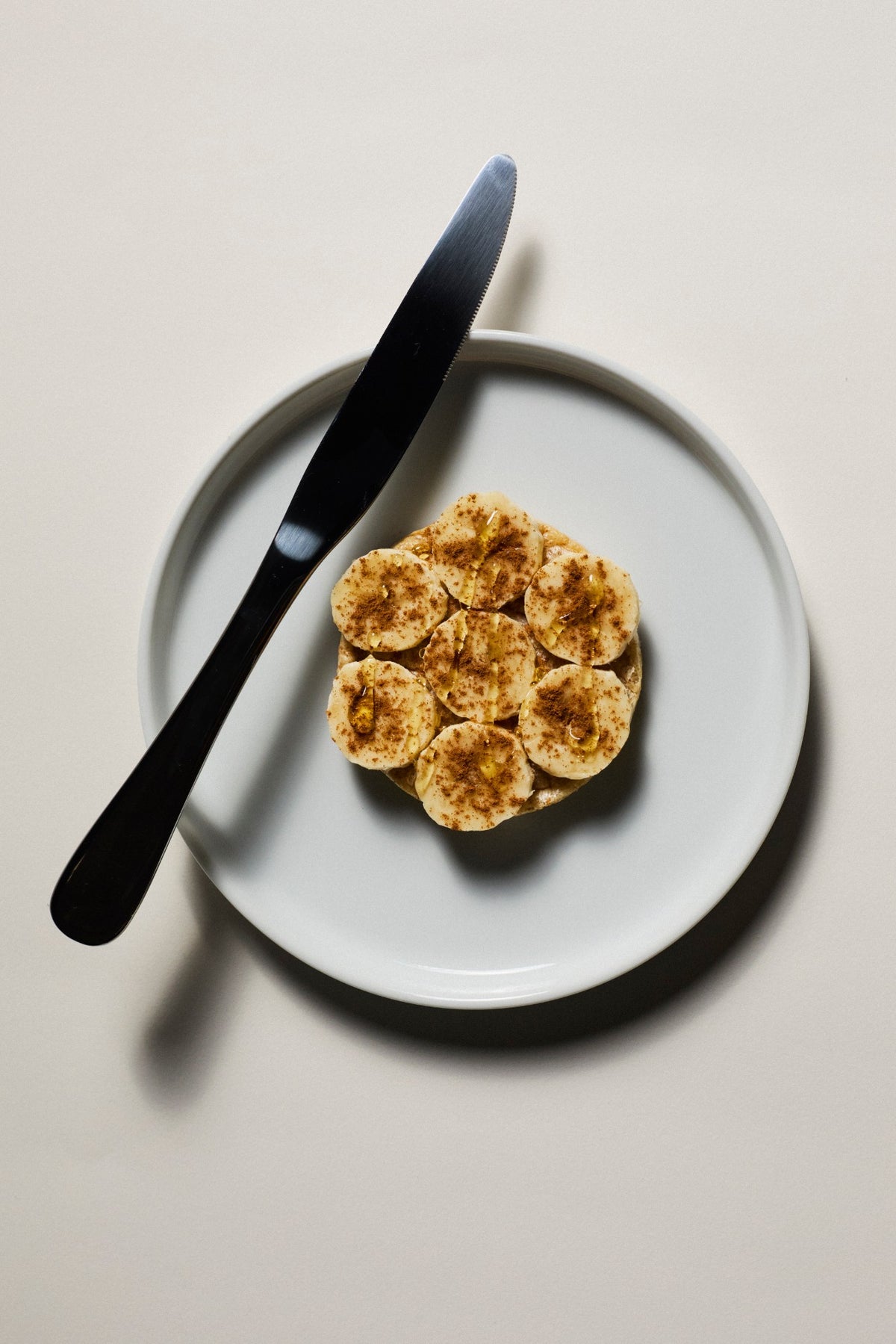A Subtle protein rice cake topped with banana on a plate.