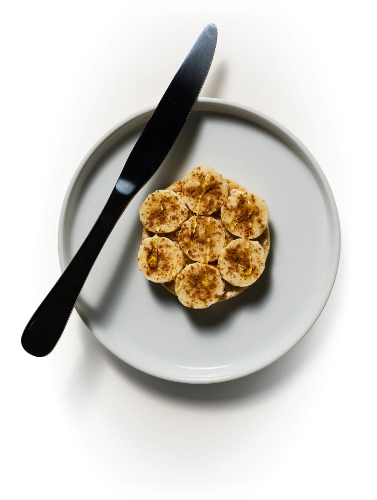 Subtle Snacks protein rice cake topped with peanut butter, banana, honey and cinnamon on a plate